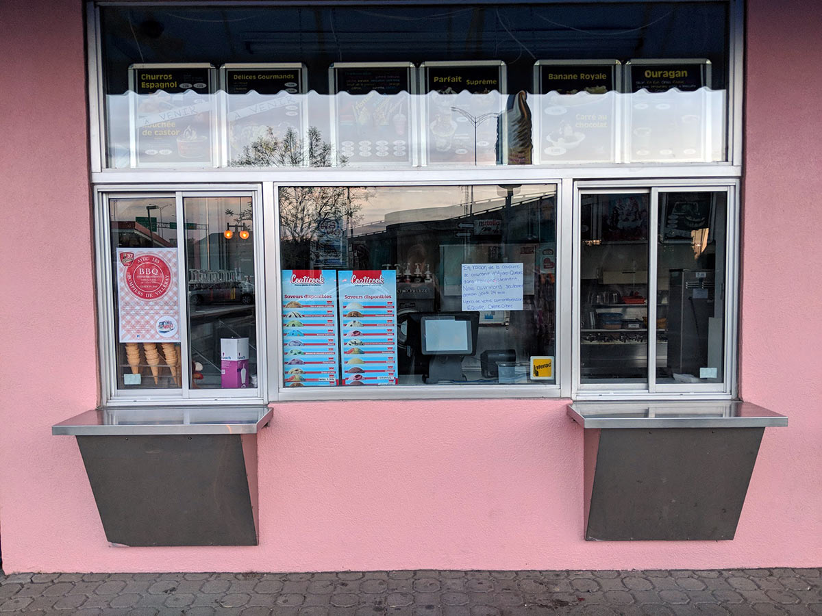 window of ice cream outdoor stand closed during the early evening with reflections of highway 40 in the background, sign on glass