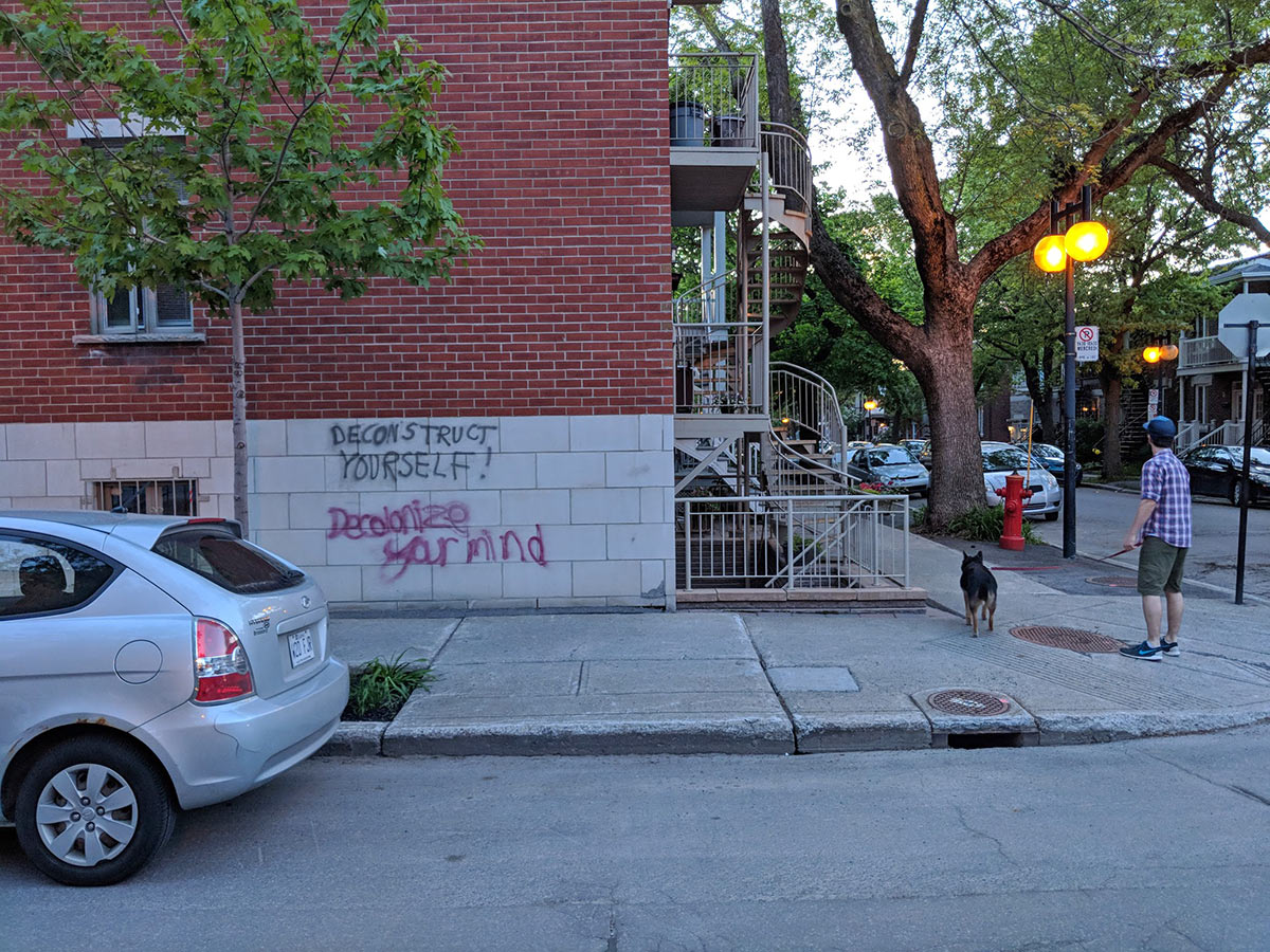 evening dog walk in quartier, message on wall: Deconstruct yourslef, decolonize your mind