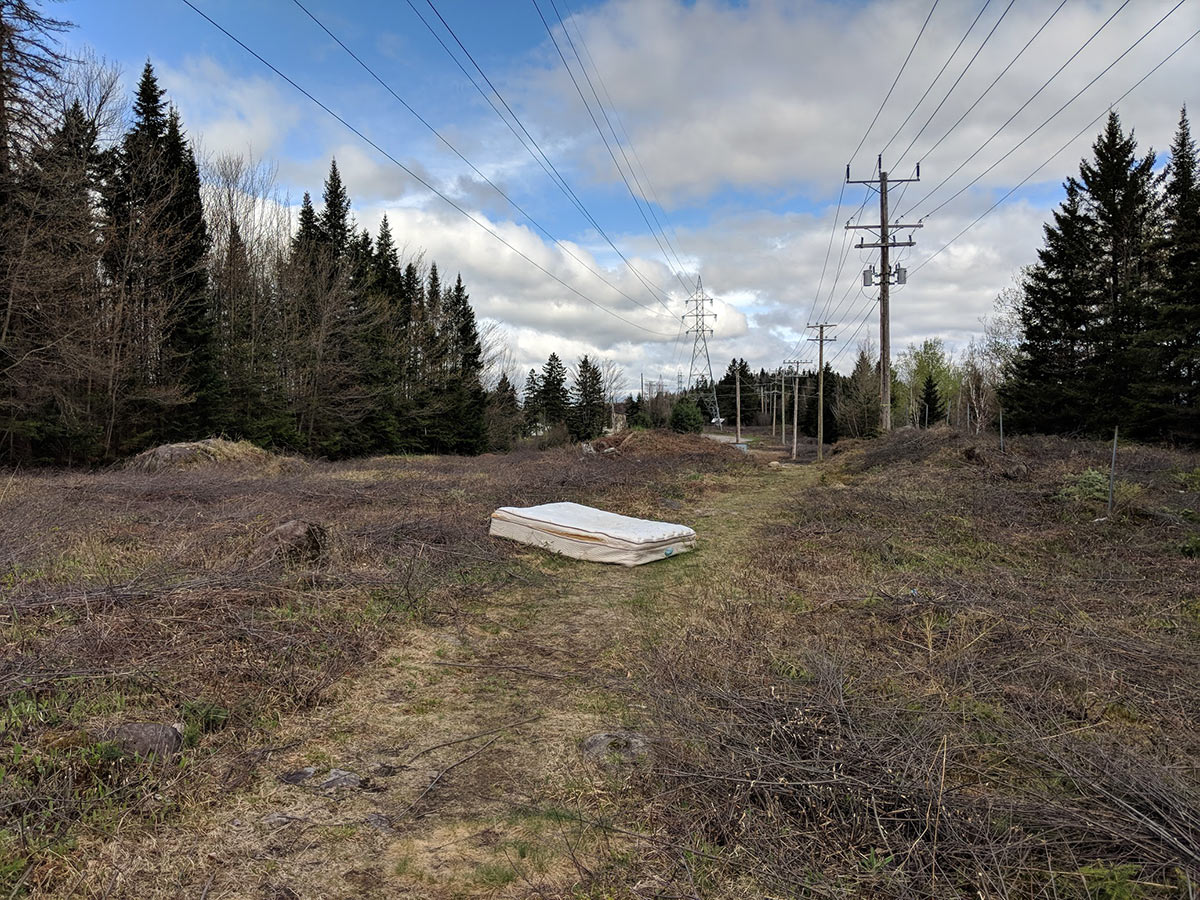 old mattress disposed in early spring, dead grass along power lines near highways