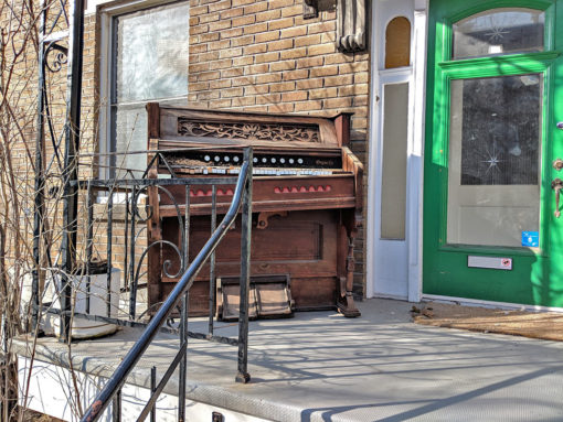 organ on the front porch in front of green door