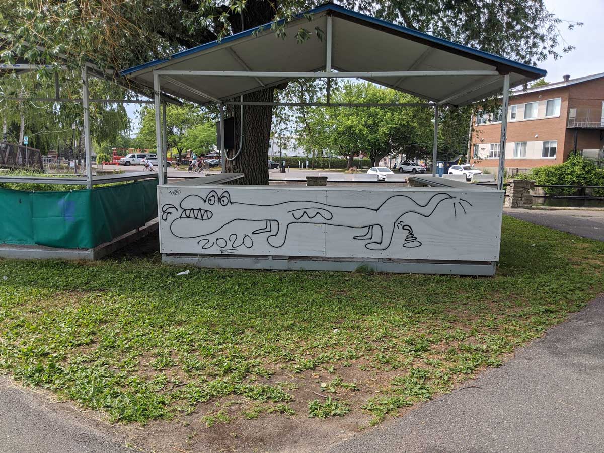 crocodile dinosaur taking a shit, had drawn on a covered seating area in a parc